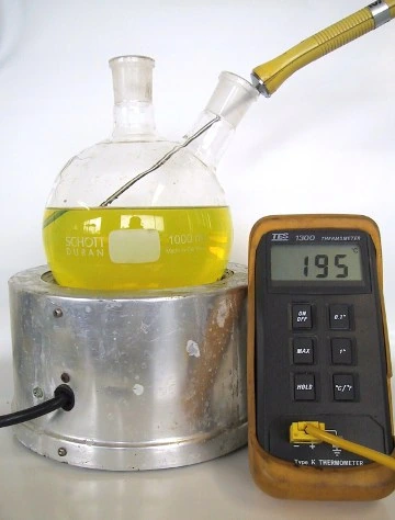 A flask of yellow Liquid Intelligence 115 on the same hotplate, the thermometer reading 195°C