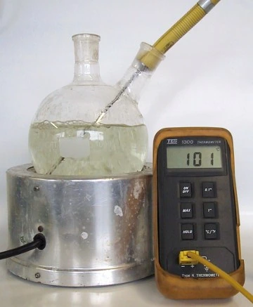 A flask of water boiling on a hotplate, the thermometer reading 101°C