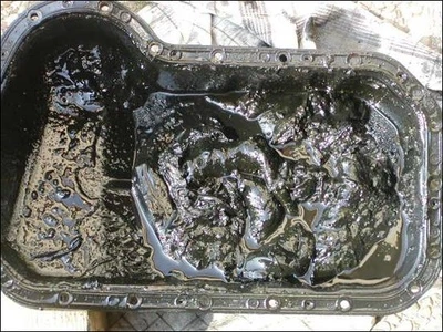An oil pan caked with thick black sludge