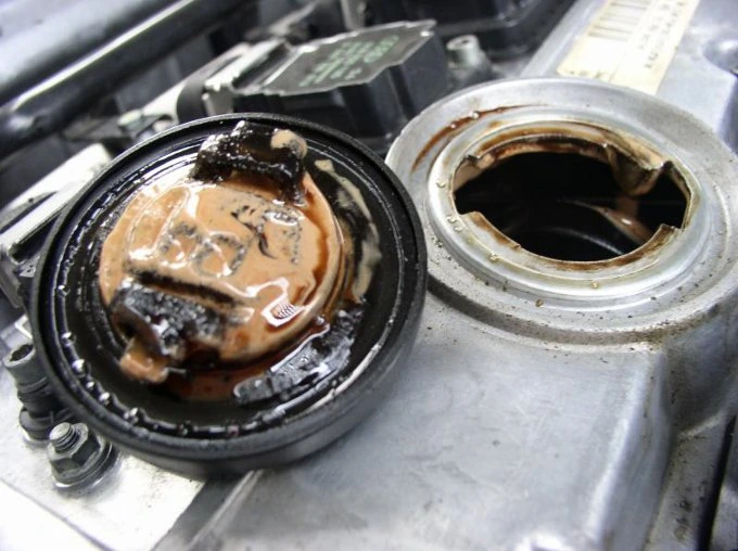 The underside of an oil filler cap coated in creamy brown oil and water emulsion