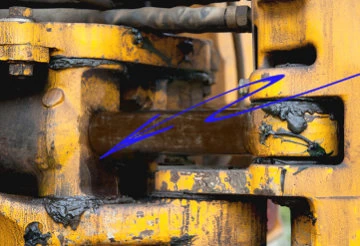 A digger's hydraulic ram with a dried, hard scraper seal; arrows point to the oil and dirt coating the rod
