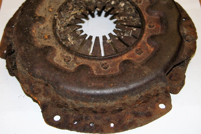 The back of a clutch pressure plate covered in thick red rust
