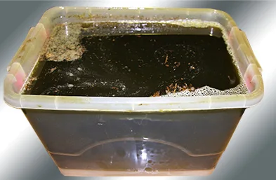 Rusty mixed-metal parts soaking in a plastic tub of 240 solution
