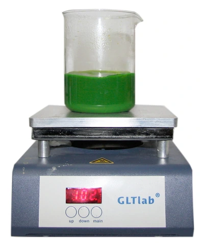 A beaker of green coolant on the hotplate reading 102°C