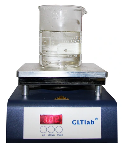 A beaker of tap water on a laboratory hotplate reading 102°C