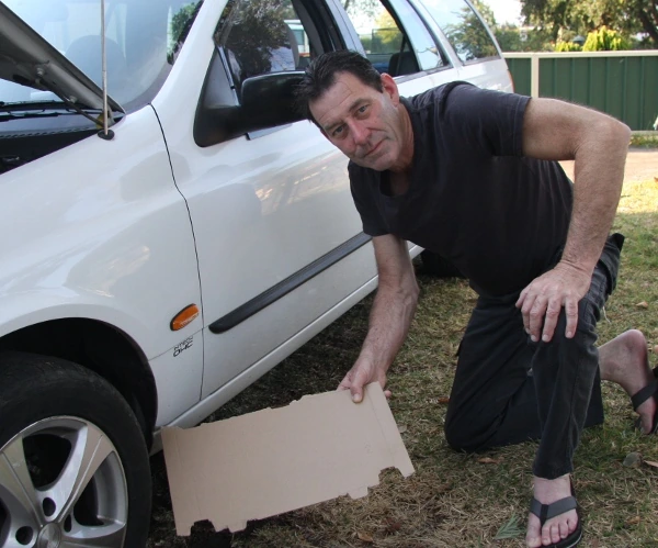Mick Meade beside his car, with the cardboard he left under it overnight